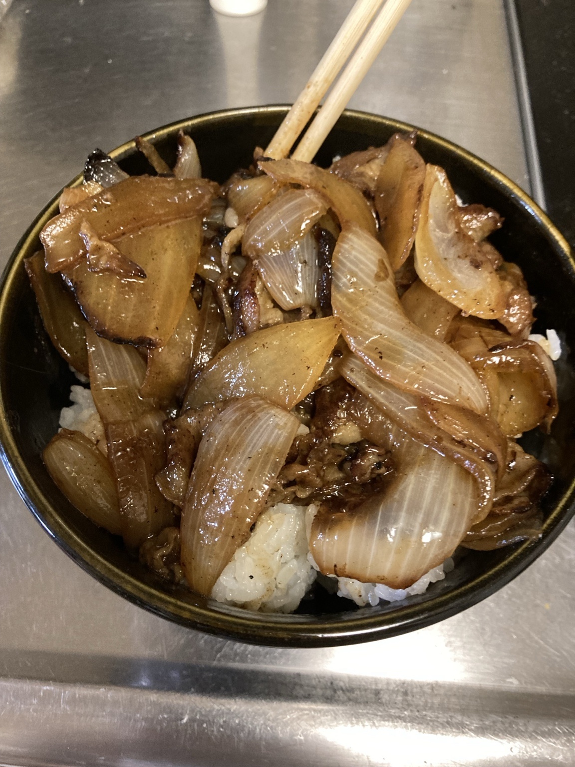タレを吸わせたご飯の上に豚バラと大量の玉ねぎを戻して盛り付けた丼